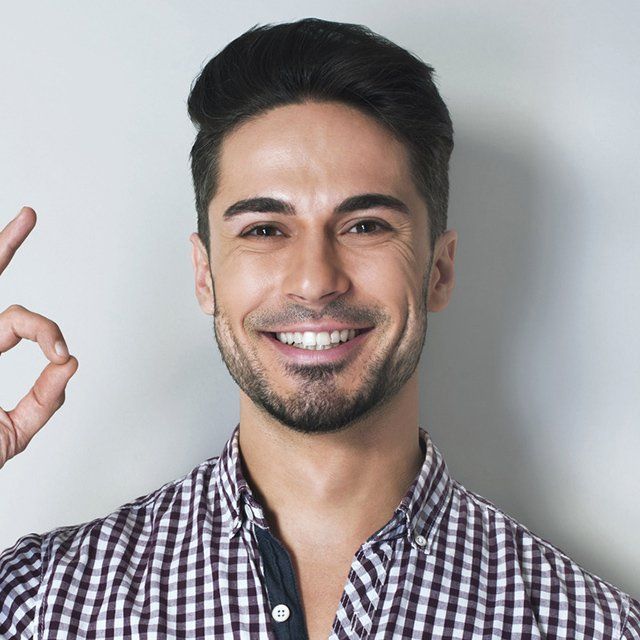 Man with dark hair smiles, making an